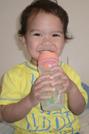 A happy toddler with a Tiwi baby tupperware bottle